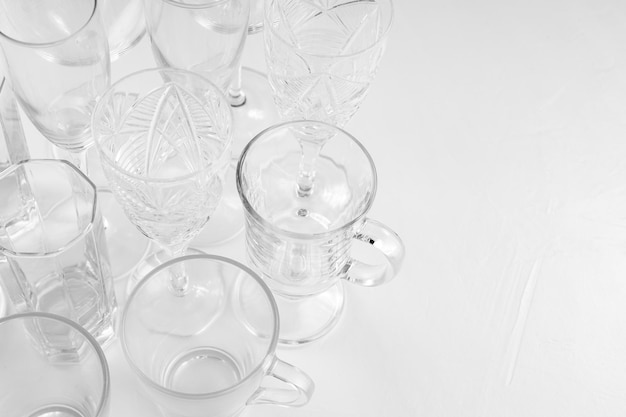 Set van geassorteerde lege drankglazen op witte achtergrond. Achtergrond van lege glazen op witte tafel. Ruimte kopiëren. Bovenaanzicht