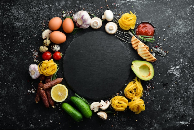 Set van gezonde voeding tomaten pasta kruiden groenten en worstjes Bovenaanzicht Zwarte stenen achtergrond