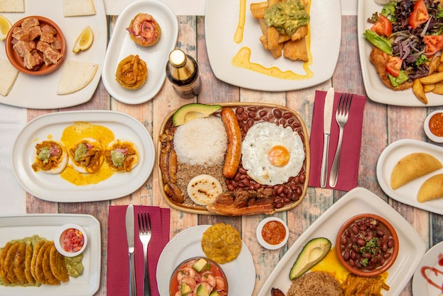 Set van heerlijke Colombiaanse recepten op houten tafel met paisa dienblad patacones chicharrones gebakken yucca met guacamole garnalencocktail en maïs arepas