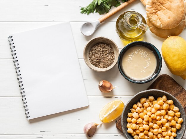 Set van ingrediënten voor het koken van zelfgemaakte traditionele hummus en witte laptop voor het schrijven van een recept. Kopieer ruimte.