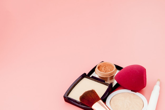 Set van kleurrijke cosmetica op roze houten tafel achtergrond, basis voor make-up in de vorm van een kussen. Kopieer ruimte