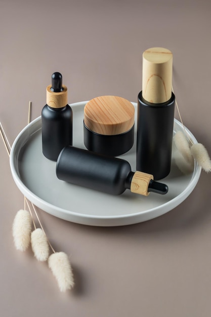 Set van natuurlijke biologische cosmetica op keramische dienblad. gezichtscrème in milieuvriendelijke bamboepot, schoonheidsolie in druppelflesje en spraylotionfles met gedroogde bloemen. huidverzorging schoonheidsproduct