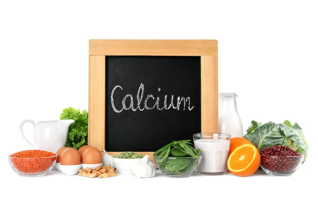 Set van natuurlijke voeding en bord met geschreven woord Calcium op witte achtergrond