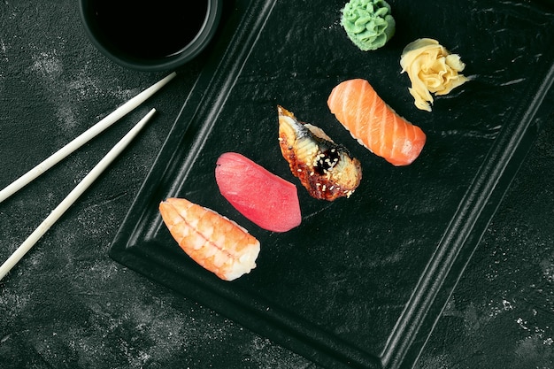 Set van Nigiri sushi met zalm, paling, tonijn, garnalen op een zwart bord. Japanse keuken. Voedsellevering. Zwarte achtergrond