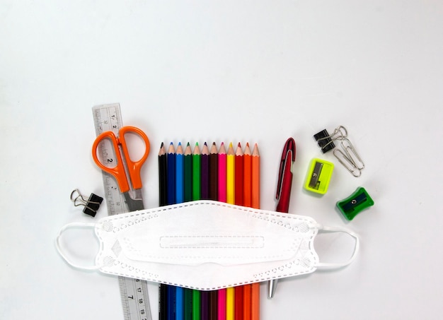 Set van onderwijs elementen kleurrijke potloden gezichtsmasker paperclips schaar liniaal geïsoleerd op wit bg