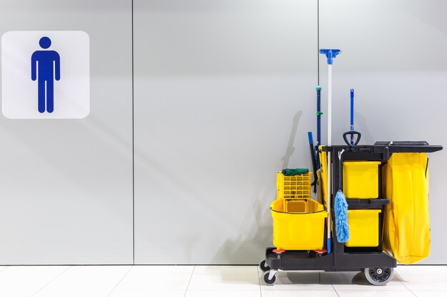 set van reinigingsapparatuur en teken van mannen toilet op de muur in de luchthaven