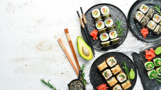 Set van traditionele sushi op een zwarte plaat Sushi en broodjes op witte houten achtergrond