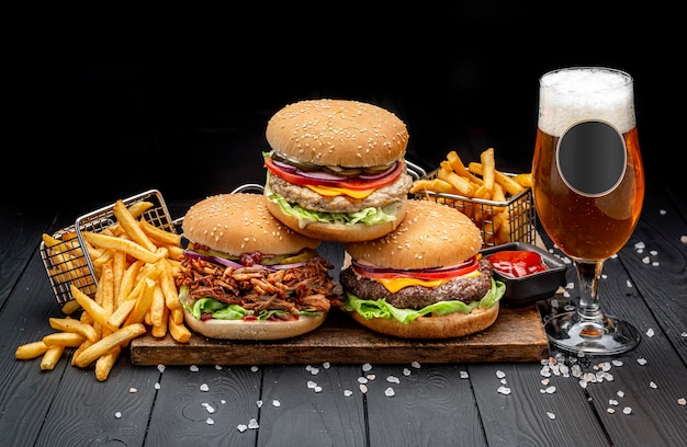 Set van verschillende hamburgers met frietjes en een glas bier hamburger met kip, rundvlees en gerookt varkensvlees