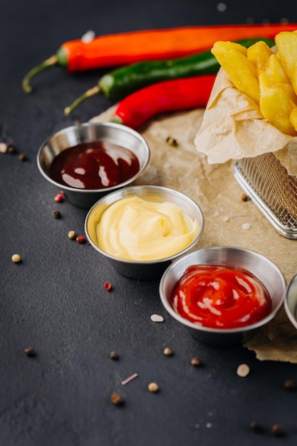 Foto set van verschillende kommen met verschillende dipsauzen tot frietjes op donkere achtergrond