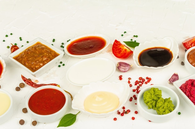 Set van verschillende sauzen - ketchup, mayonaise, barbecue, soja, chutney, wasabi, adjika, mierikswortel, aioli, marinara. Witte stopverfachtergrond, kopieer ruimte