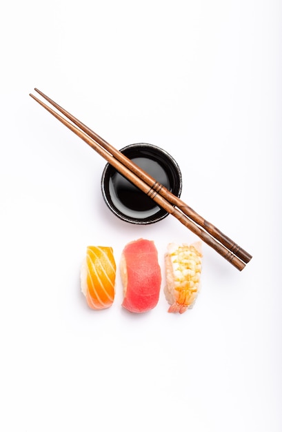 Set van verschillende sushi met zalm, tonijn en garnalen, sojasaus en eetstokjes op witte achtergrond, bovenaanzicht. Traditioneel Japans sushiconcept, close-up, plat leggen