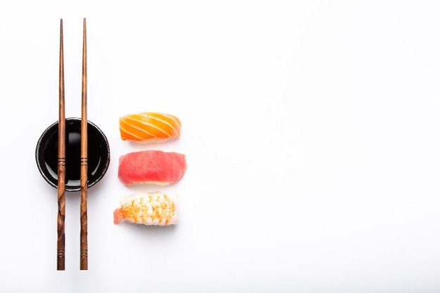 Set van verschillende sushi nigiri, sojasaus en eetstokjes op witte achtergrond met kopie ruimte, bovenaanzicht. Traditioneel Japans sushiconcept, close-up