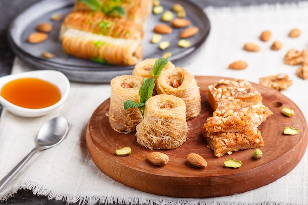 Set van verschillende traditionele Arabische zoetigheden: baklava, kunafa, basbus in keramische platen op een grijs beton. zijaanzicht.