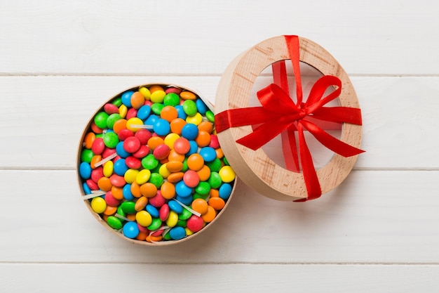 Set van verschillende zoete snoepjes in een papieren doos met een satijnen lint op een gekleurde achtergrond Vakantie concept