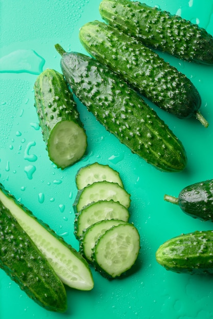 Set van verse hele en gesneden komkommers op een groene achtergrond met waterdruppels. Tuin komkommer behang achtergrond ontwerp