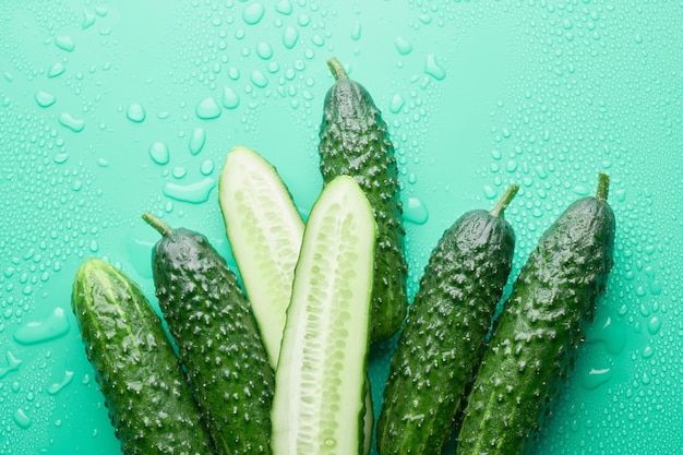 Set van verse hele en gesneden komkommers op een groene achtergrond met waterdruppels. tuin komkommer behang achtergrond ontwerp