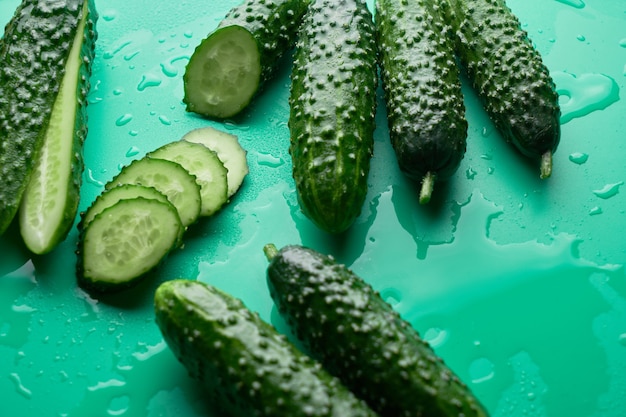 Set van verse hele en gesneden komkommers op een groene achtergrond met waterdruppels. Tuin komkommer behang achtergrond ontwerp