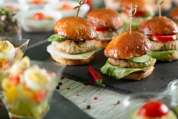 Set van vlees hamburgers op zwarte bord op houten tafel