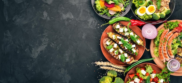 Set van voedsel Kipfilet gegrilde worstjes aubergine cherrytomaatjes verse groenten Op de stenen tafel Bovenaanzicht Vrije ruimte voor tekst