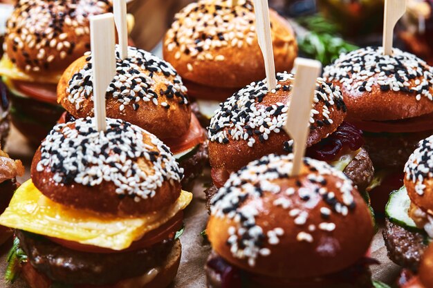 Set van zelfgemaakte heerlijke hamburgers gemaakt van rundvlees, spek, kaas, salade en tomaten op een donkere betonnen achtergrond. Vette ongezonde kost dichte omhooggaand. Met kopie ruimte. Fast food patroon