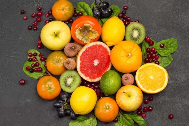 Set of varied, multicolored exotic fruits. Tangerines and oranges, kiwi and pear, persimmon and lychee. Black Background. Flat lay
