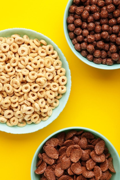 Set of various breakfast cereals on yellow background Vertical photo