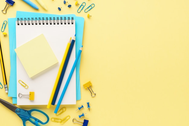 Set of various colorful school stationery and supplies on yellow background.