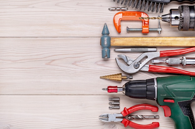 Set of various home tools lying in row on light wooden