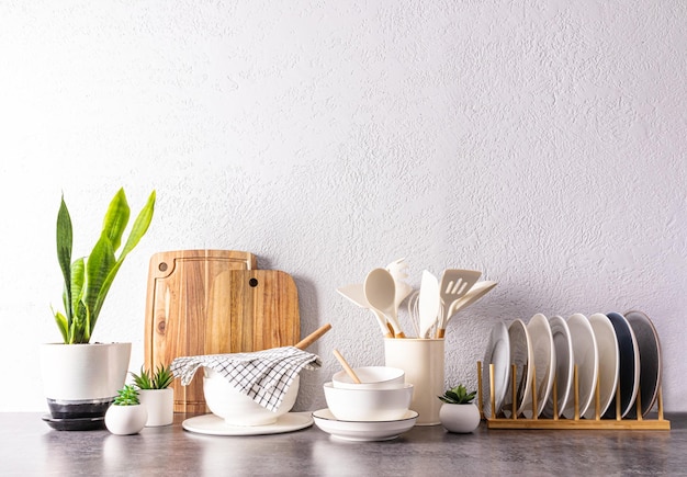 A set of various kitchen utensils and tools ceramic dishes in light colors on a modern kitchen countertop front view a copy space