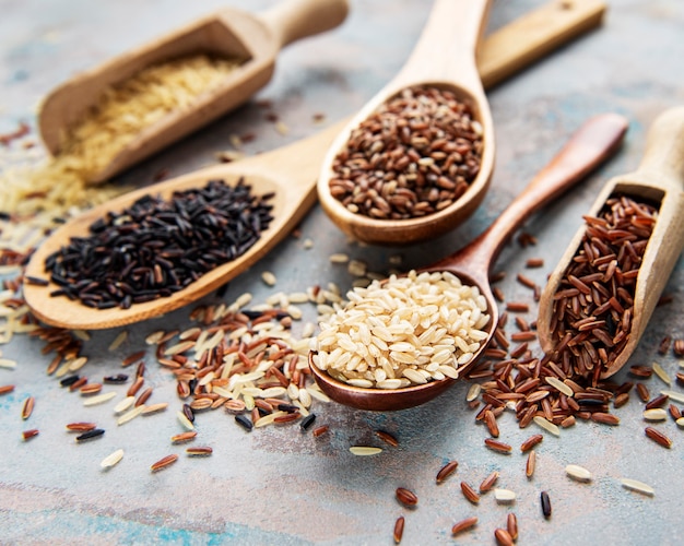 Set of various rice on concrete table: black, basmati, brown and red mixed rice