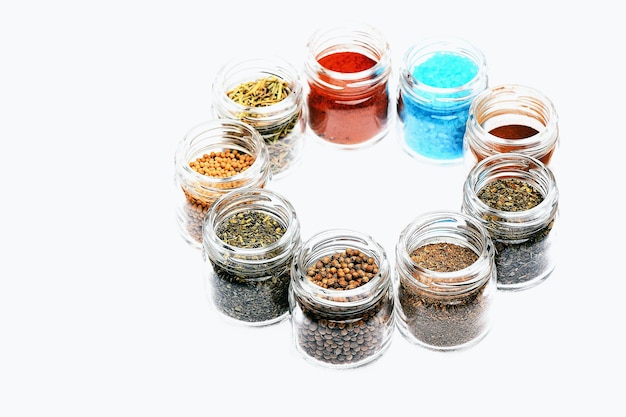 set of various spices: rosemary, paprika, mustard, cinnamon, coriander, salt in jars laid out in circle isolated on white background, side view, copy space