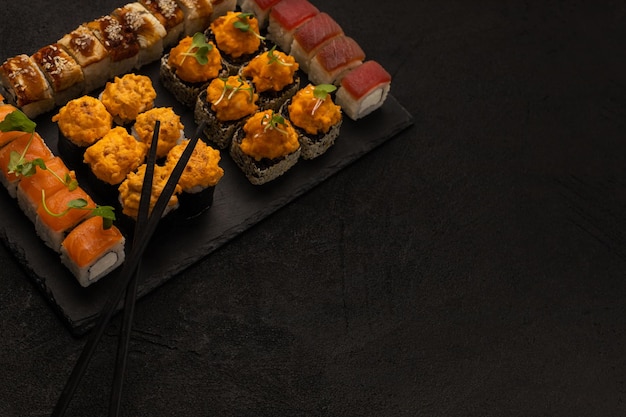 Set of various sushi rolls Japanese food on a black board for serving on a black background