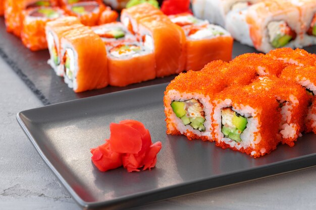 Set of various sushi rolls served on gray close up