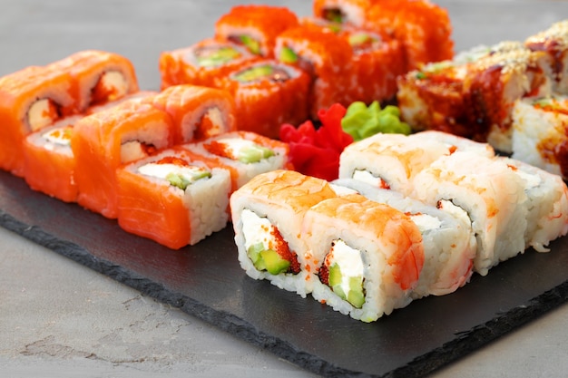 Set of various sushi rolls served on gray