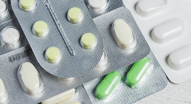 Set of Various Tablets and Capsules in Blisters on White Wooden. Medicine Concept.