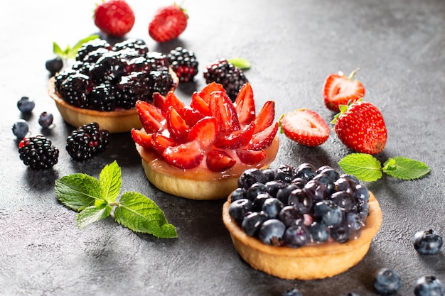 Set of various tartlets or cakes with cream cheese and summer berries. Confectionery desserts.