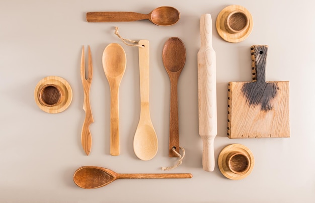 A set of various wooden spoons cups and a cutting board on a light background top view flat styling kitchen background