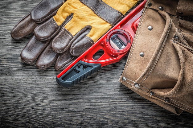 Set veiligheidshandschoenen op constructieniveau lederen gereedschapsriem op houten plank