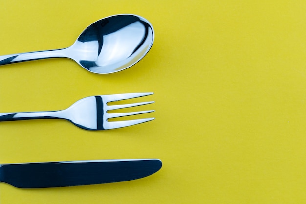 Set vork, mes en lepel geïsoleerd op geel papier achtergrond.