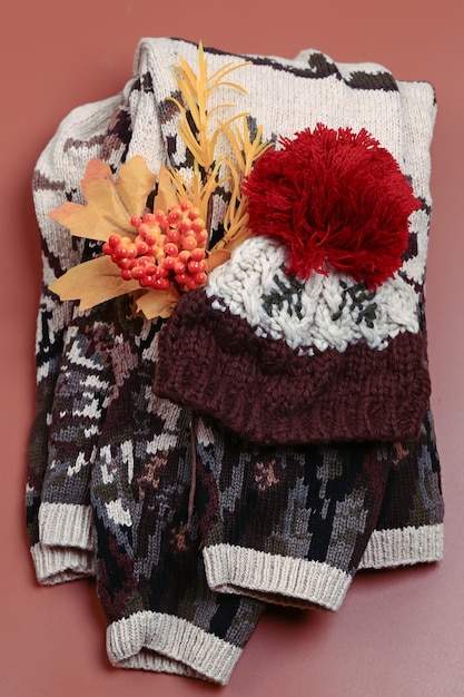베이지색 배경의 탑 뷰 니트 스웨터와 모직 모자 플랫 스타일의 따뜻한 가을 옷 세트...