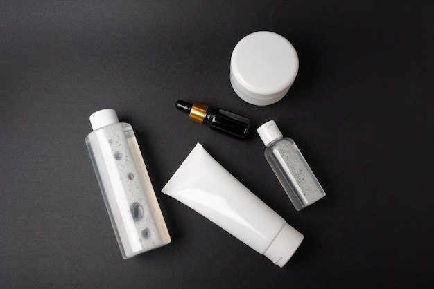 A set of white and black cosmetics lies on a black background