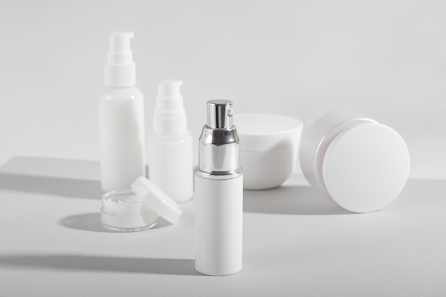 Set of white cosmetic bottles and jars with hard shadows. Home and beauty salon care concept