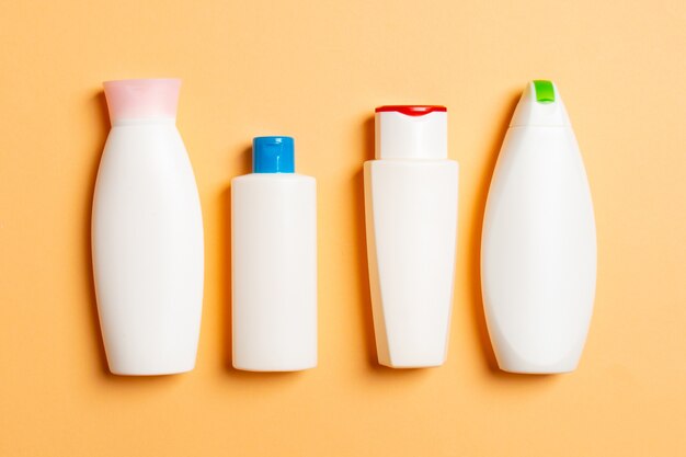 Набор белых косметических контейнеров, изолированных на цветном фоне, вид сверху с копией пространства. Группа пластиковых контейнеров для бутылочек с пустым пространством для вас.