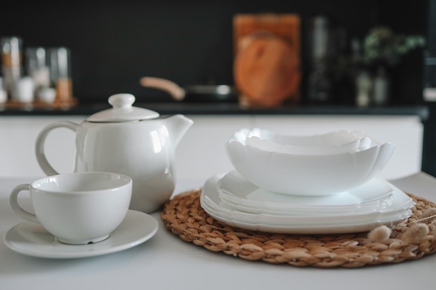 Set of white minimalist dishes on a table against the backdrop of a kitchen