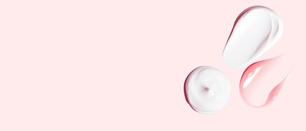 Set of white and pink cream strokes on a pink background empty space