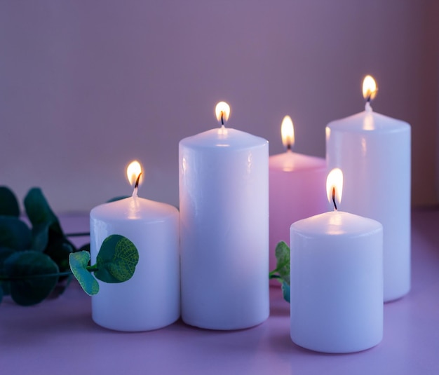 Foto set di candele in cera bianca e rosa con foglie verdi