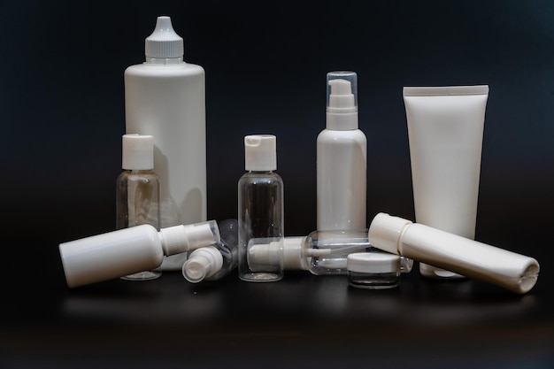 Set of white plastic bottles packages tubes on black background\
for cosmetic product for cream bottle with spray oil lotion or\
shampoo gel or soap
