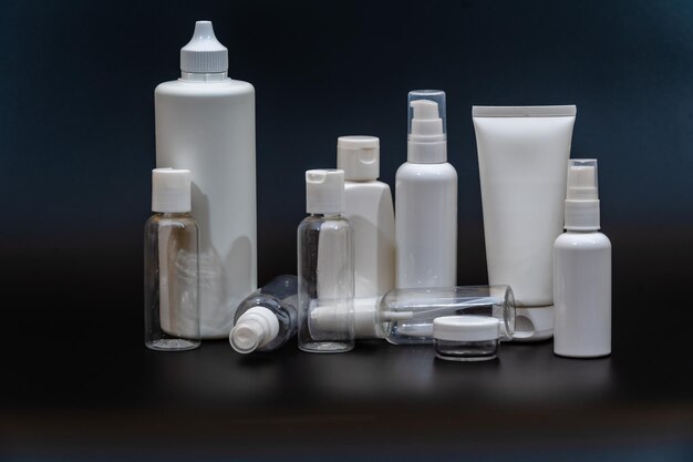 Set of white plastic bottles packages tubes on black background\
for cosmetic product for cream bottle with spray oil lotion or\
shampoo gel or soap