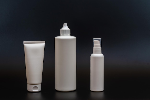 Set of white plastic bottles packages tubes on black background
for cosmetic product for cream bottle with spray oil lotion or
shampoo gel or soap