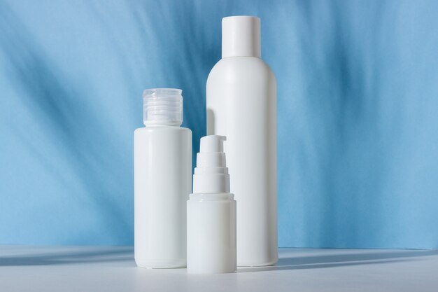 Set witte cosmetische flessen en potten met harde schaduwen. thuis- en schoonheidssalon zorgconcept